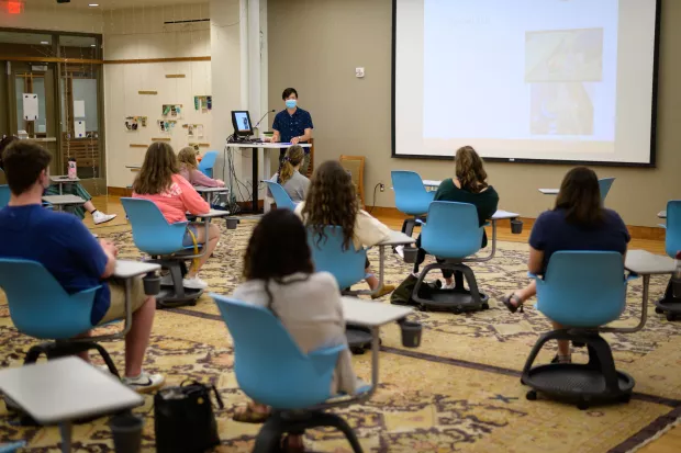 Students sitting in a classroom during InterVarsity large group with a speaker in the front of the room