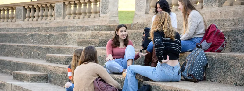 Students sitting on steps, engaged in a discussion.