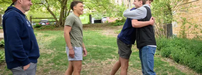 Four men outside, two of them hugging