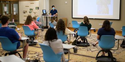 Students sitting in a classroom during InterVarsity large group with a speaker in the front of the room