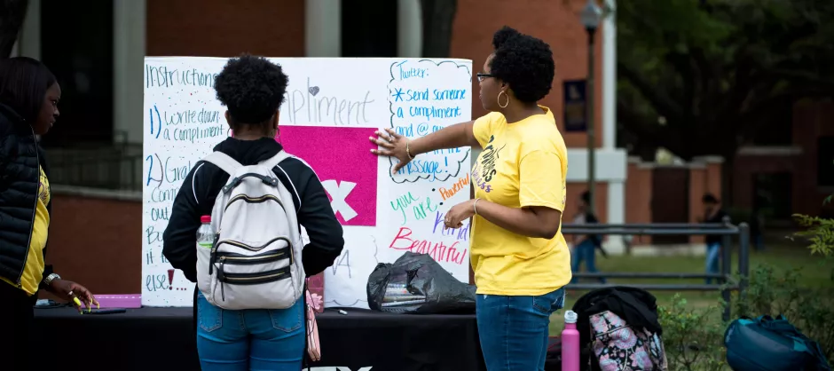 One InterVarsity student leader with another student at a proxe station outdoors.