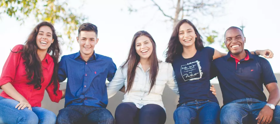 A diverse group of friends sitting on a bench on a sunny day