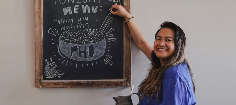Girl standing next to chalk board