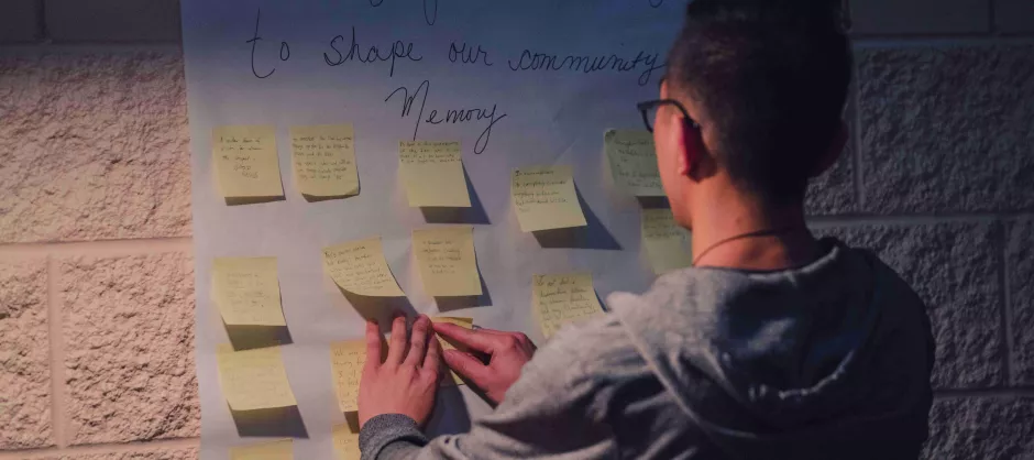 a photo of a young man putting sticky notes onto a wall