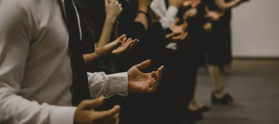 people standing with palms up in a posture of prayer