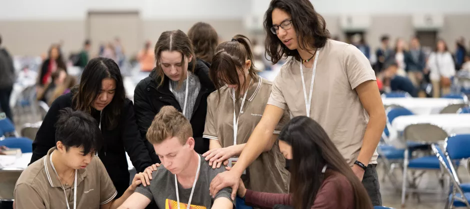 A small group at Urbana laying hands around a student in prayer