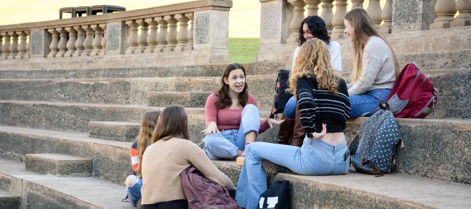 Students sitting on steps, engaged in a discussion.