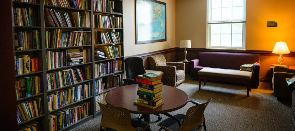 room with a table, couch, and bookcase with books