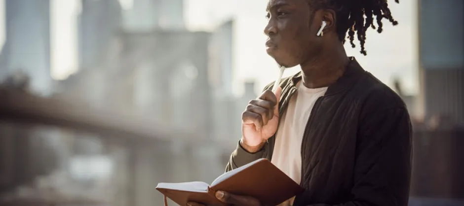 young man pondering with a journal