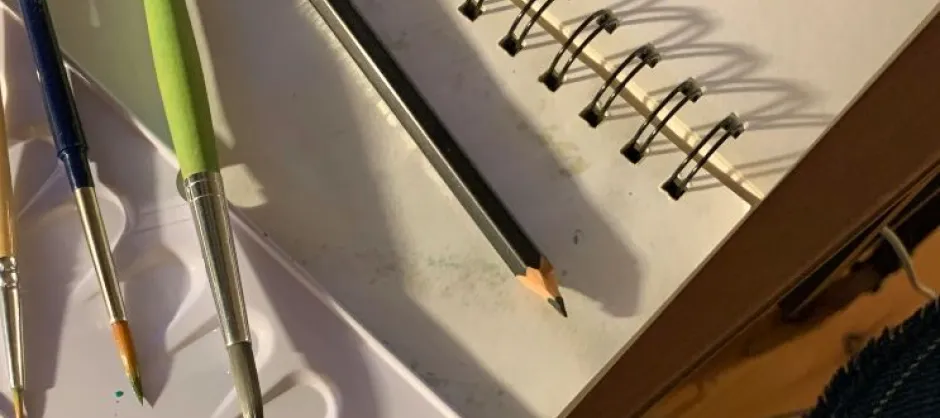 notebook with paintbrushes and a pencil
