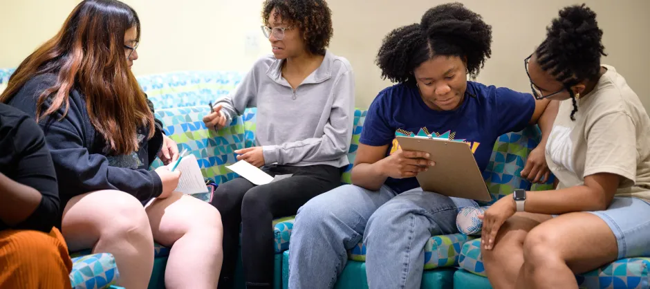 Four students in pairs discussing with manuscripts.