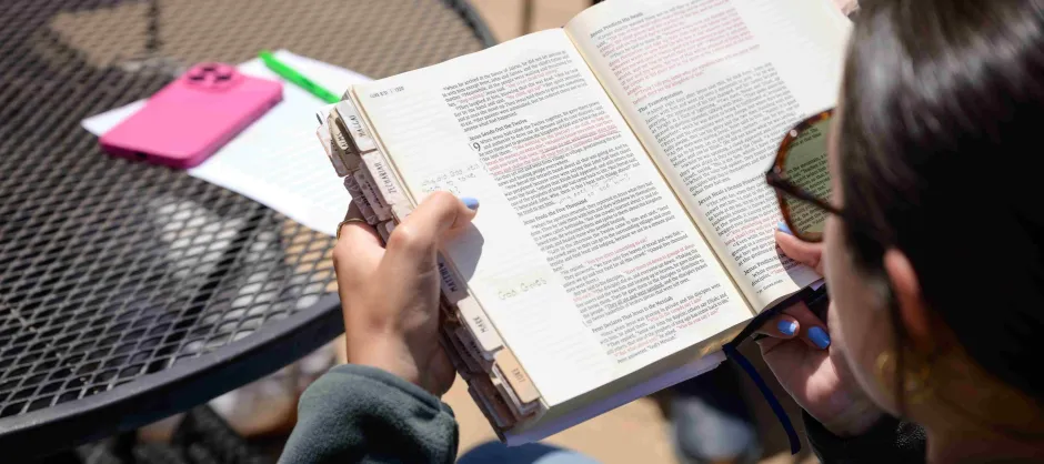 A woman outdoors, deeply focused on the Bible while enjoying the fresh air.