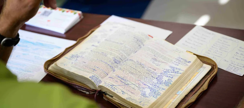 A person sits at a desk with a Bible open