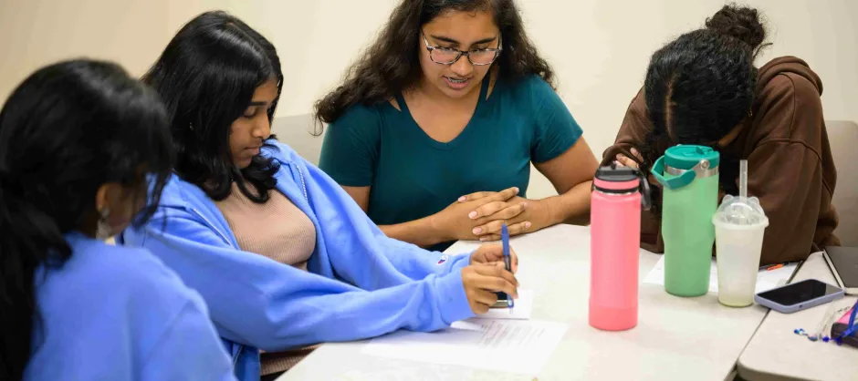 A group of students around a desk praying after Bible Study.