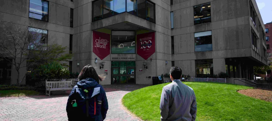 two faculty walking and approaching a campus building