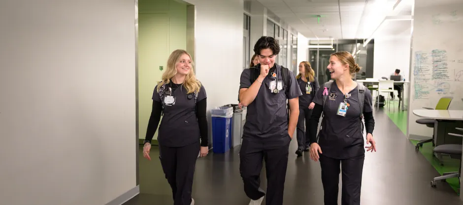 Three people in scrubs walking down a hall