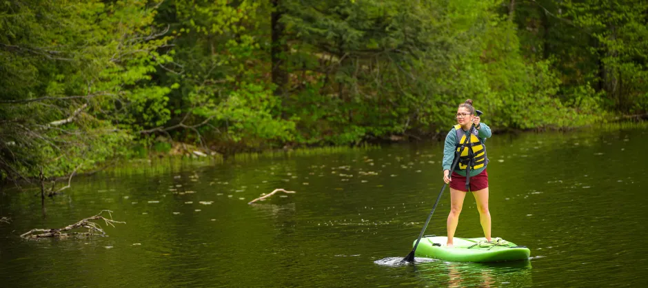 A woman paddleboarding in a stream.