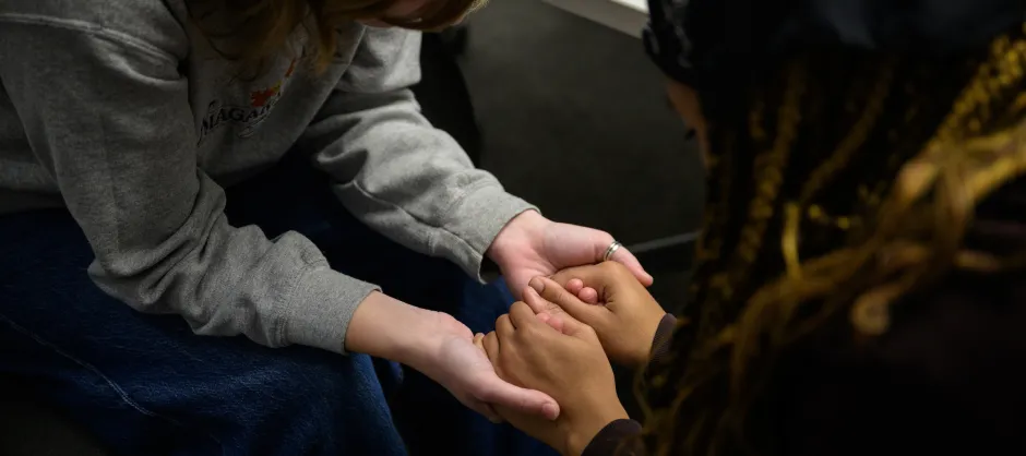 Two students holding hands and praying