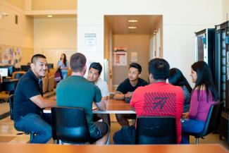 a group of students sitting around a table intently looking at each other