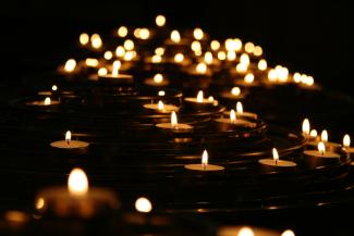 A group of lit candles on the ground in an otherwise dark room.