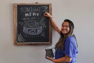 Girl standing next to chalk board