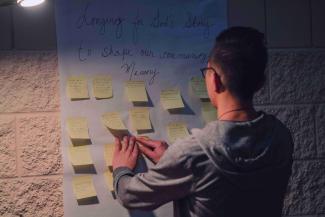 a photo of a young man putting sticky notes onto a wall