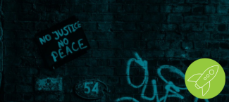Dark cyan brick wall with a sign propped up reading "No Justice No Peace"  