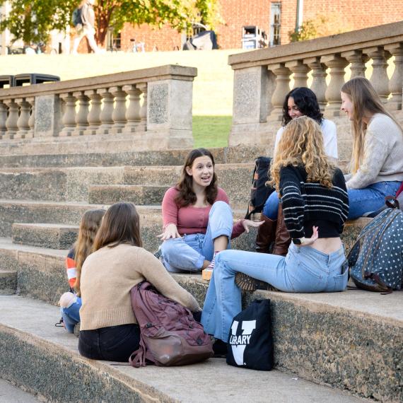 Students sitting on steps, engaged in a discussion.